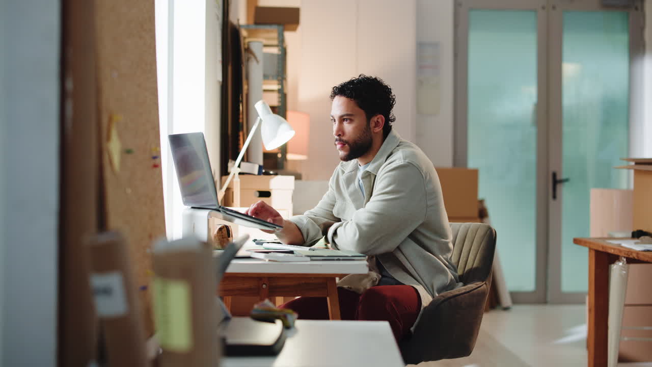Giovane uomo che lavora al laptop alla scrivania in un ufficio moderno