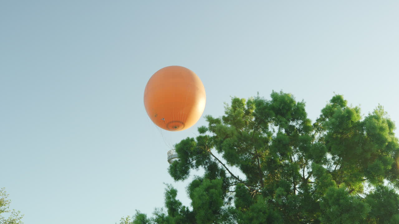 a medida que la cámara sale de detrás de un árbol, vemos el gran globo naranja en el gran parque del condado de orange ubicado en irvine california