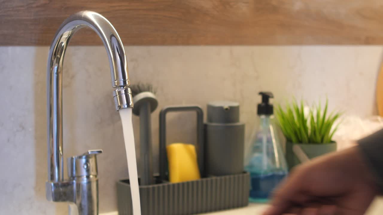 persona lavándose las manos en un fregadero de la cocina