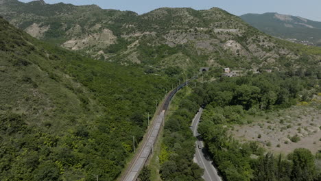 vagón de tren largo que viaja por las faldas del túnel de montaña en mtskheta, georgia