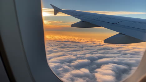 airplane wing view over clouds at sunset or sunrise
