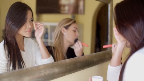 chicas poniendo maquillaje frente a un espejo