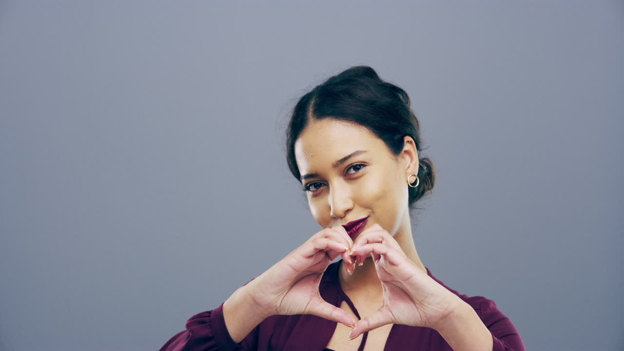 젊은 여성 이 손 으로 심장 모양 을 만들고 있다