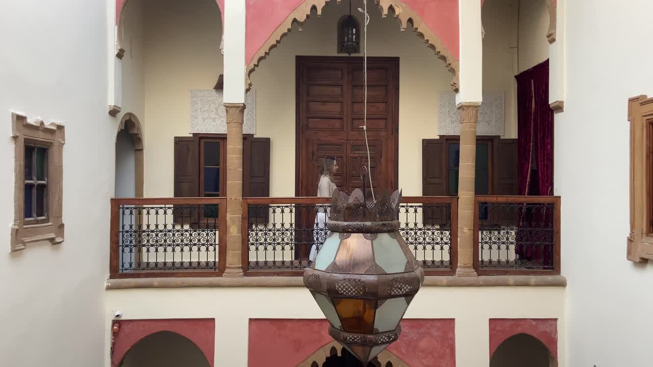 una turista rubia caucásica caminando por las habitaciones de un riad marroquí.