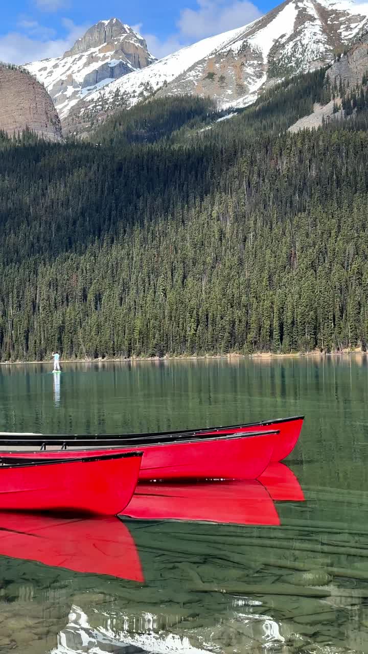 Person beim Stand-Up-Paddling auf türkisfarbenem Wasser mit den Kanadischen Rocky Mountains im Banff-Nationalpark, Kanada
