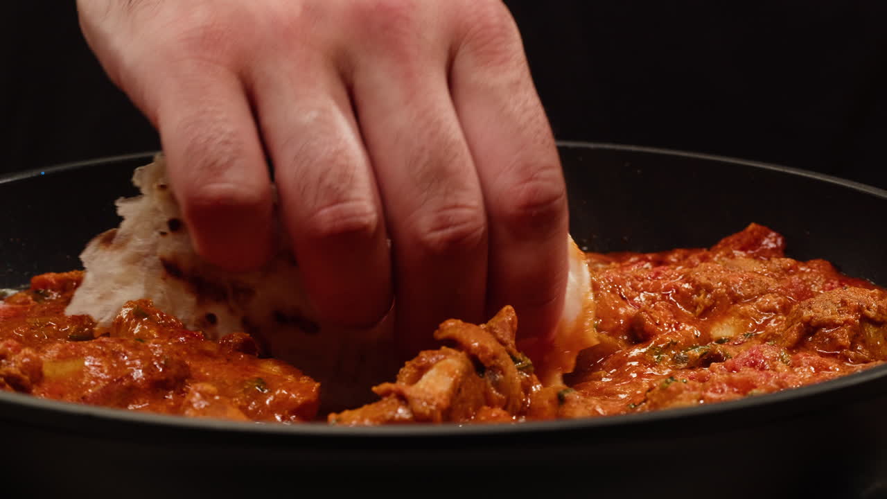 Close up of food with hand dipping flatbread in sauce