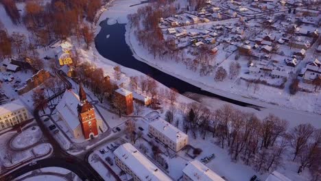 beautiful aerial view over valmiera during the winter, showing snowy houses, buildings, river gauja and church under the warm glow of afternoon sun