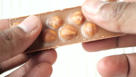 hands holding and breaking a piece of hazelnut chocolate bar