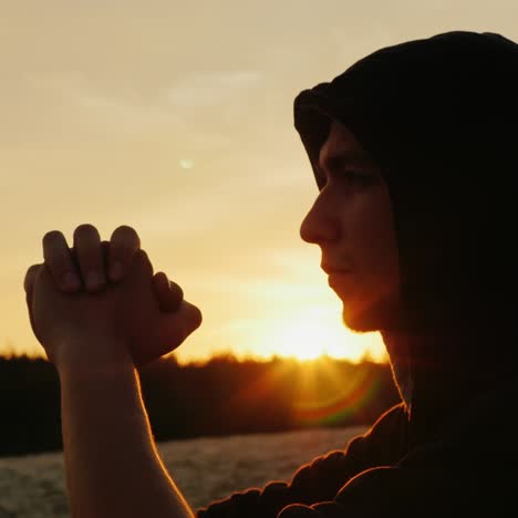 A-young-man-in-a-hood-prays-at-sunset-1