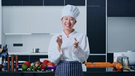 asian woman chef smiling and clapping her hands in home kitchen