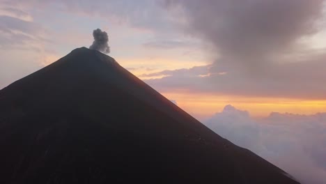 volcano erupting in the sunset with people close by