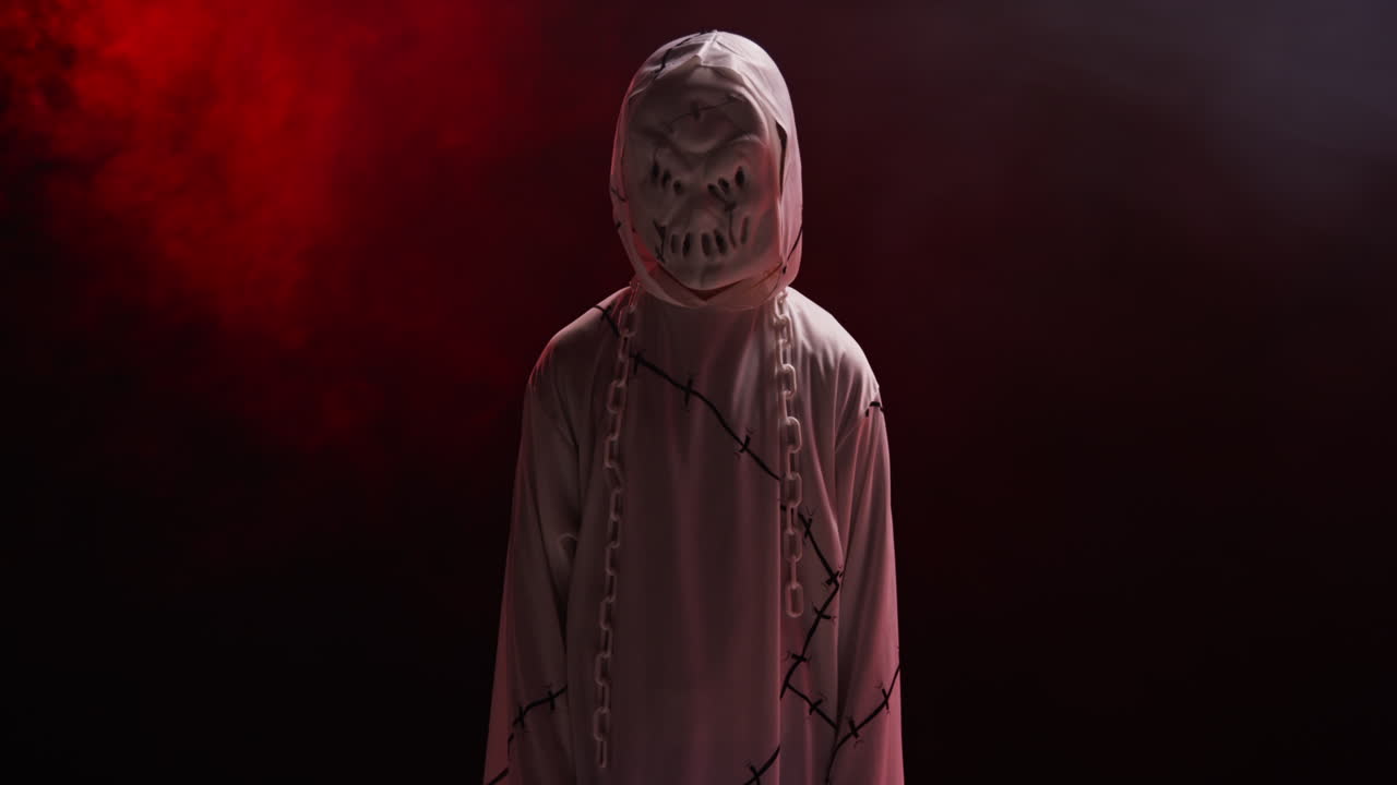 niño vestido de fantasma zombie monstruo disfraz truco o trato en halloween asustando a la gente contra el fondo de humo rojo 6