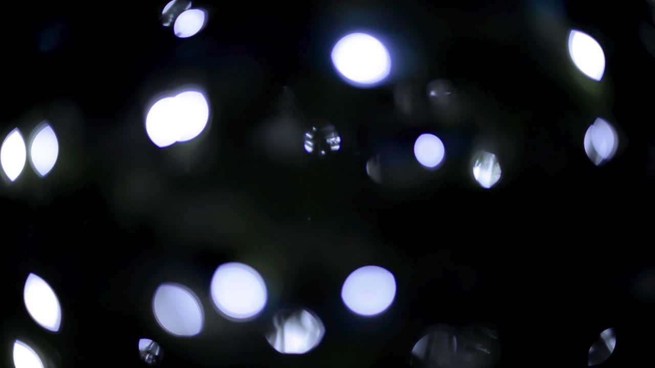Hermosas luces bokeh azules parpadeando con un fondo negro.