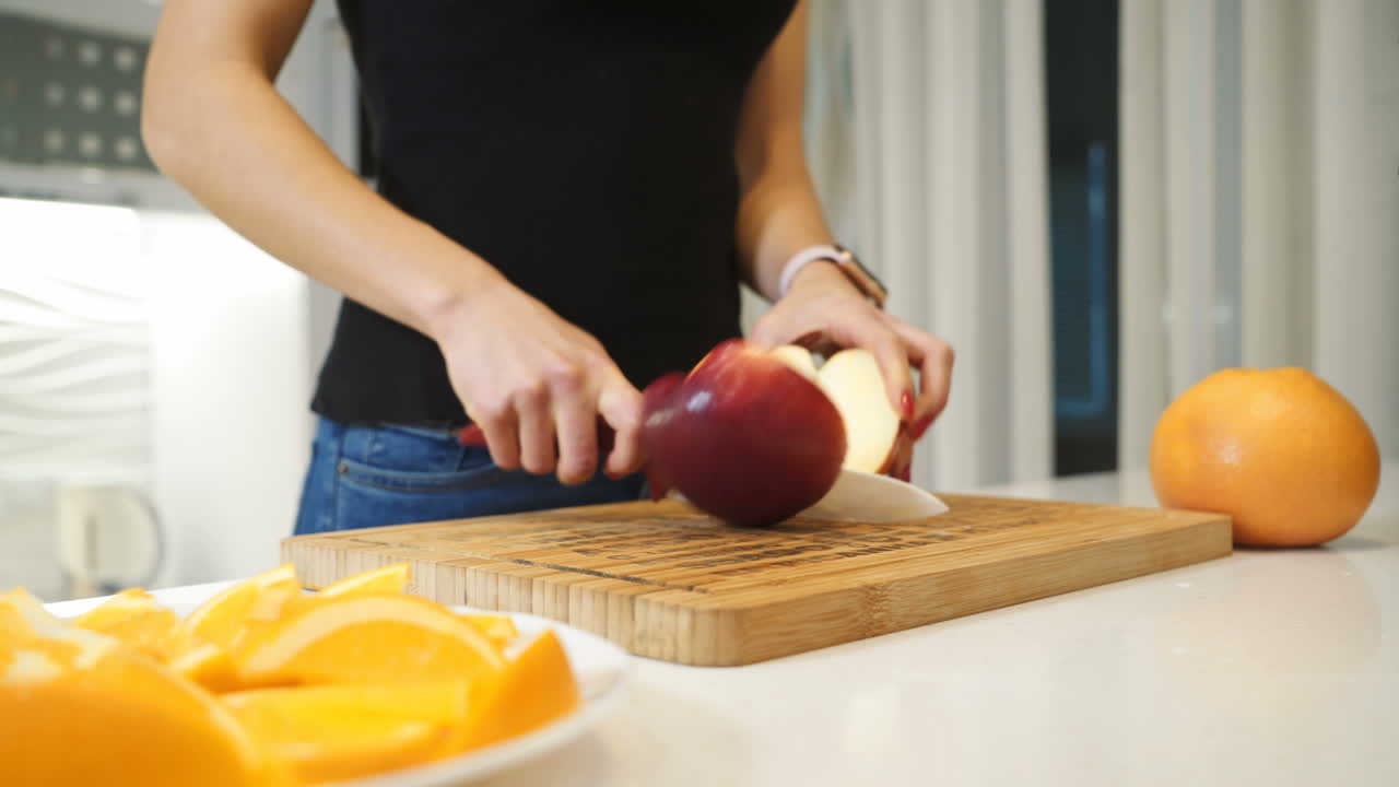 Young woman cutting a large red apple on a wooden board. Healthy lifestyle. Fresh fruits.