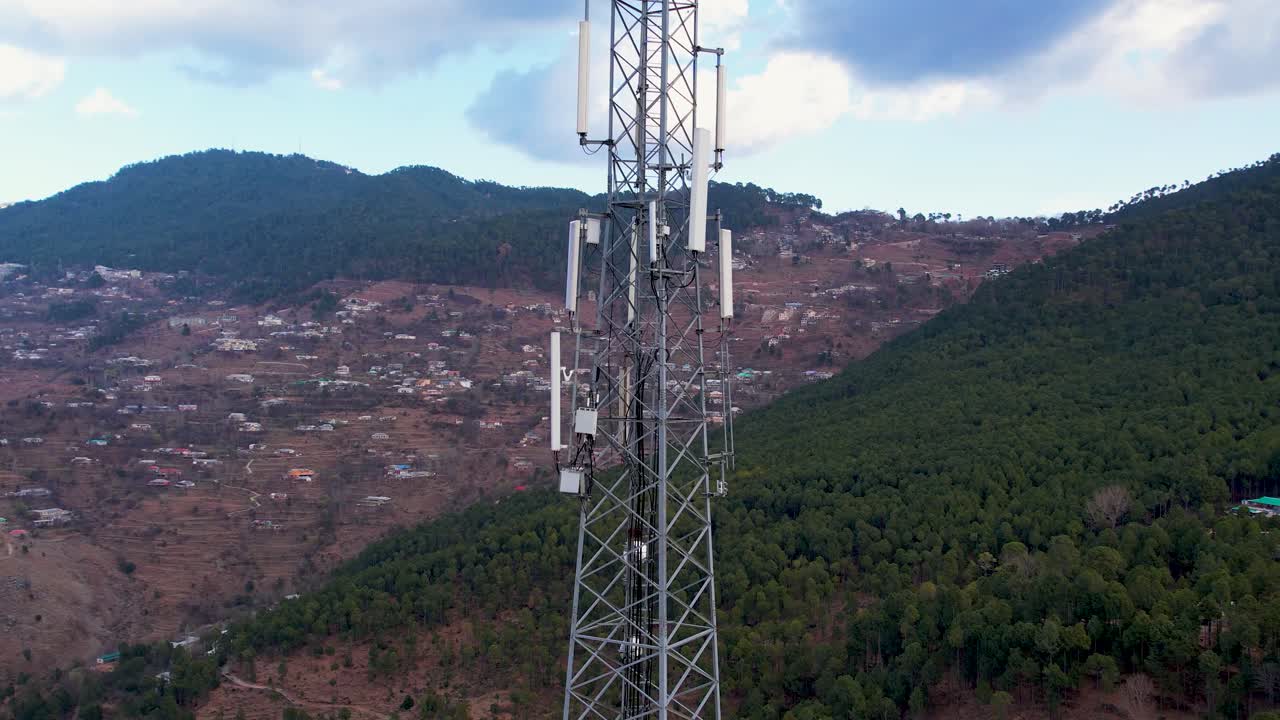 Tall mobile tower stands amidst forested hills providing network access to remote mountain villages