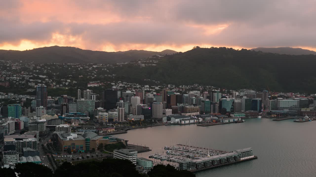 Time lapse of moving clouds over Wellington city at sunset time. Marina ich yachts and waterfront. Aerial wide shot. Mountains range in background. Capital of New Zealand.