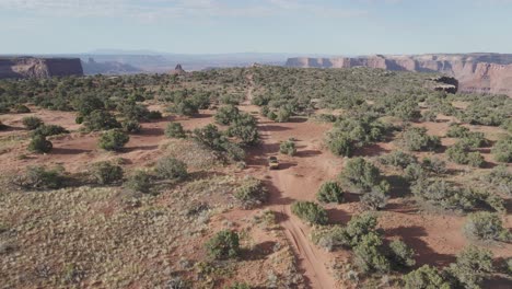 aerial-mustard 4x4 vehicle crossing canyon landscape in moab,utah