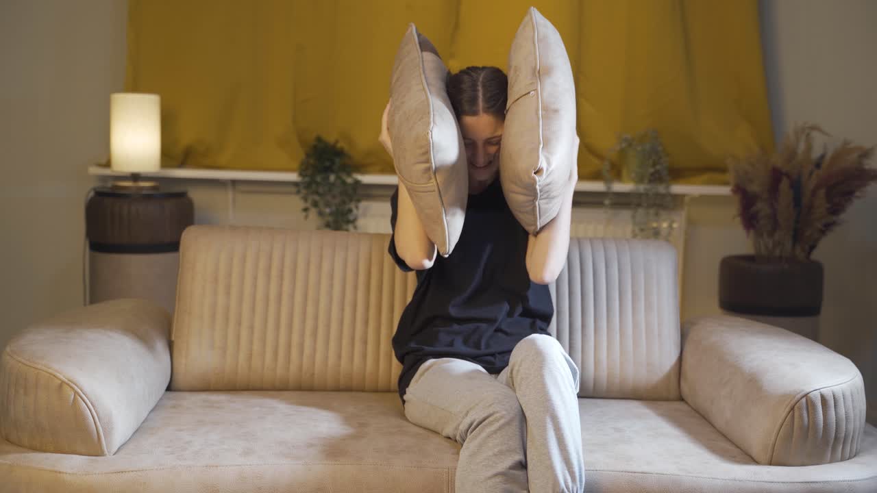 두려움으로 머리에 베개를 누르는 젊은 여성.