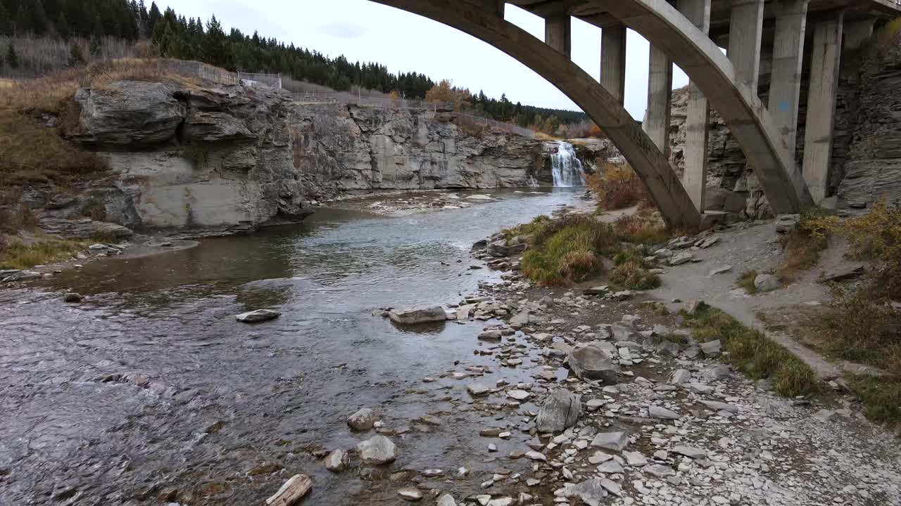 룬드브렉에 접근하는 슬로모션 항공 샷이 캐나다 앨버타 남부의 아치교 아래에서 비행하는 동안 추락합니다.