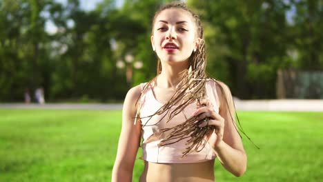 young beautiful girl with dreads dancing in a park. beautiful woman in jeans listening to music and dancing during a sunny day