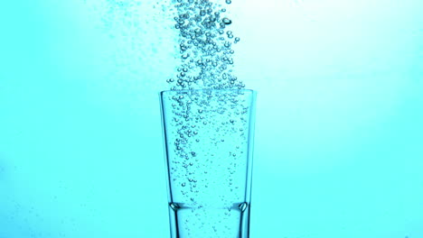 bubbles rising from glass submerged in blue water