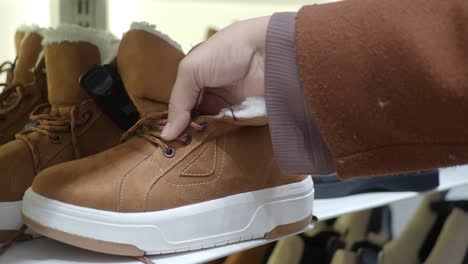 woman looking at brown winter boots in a store