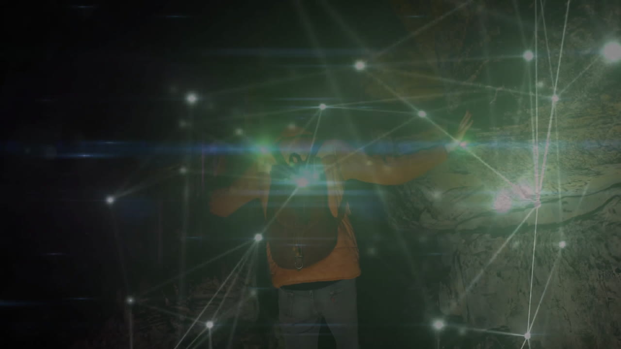 man exploring dark cave tunnel, projecting glowing green light and technology network overlay