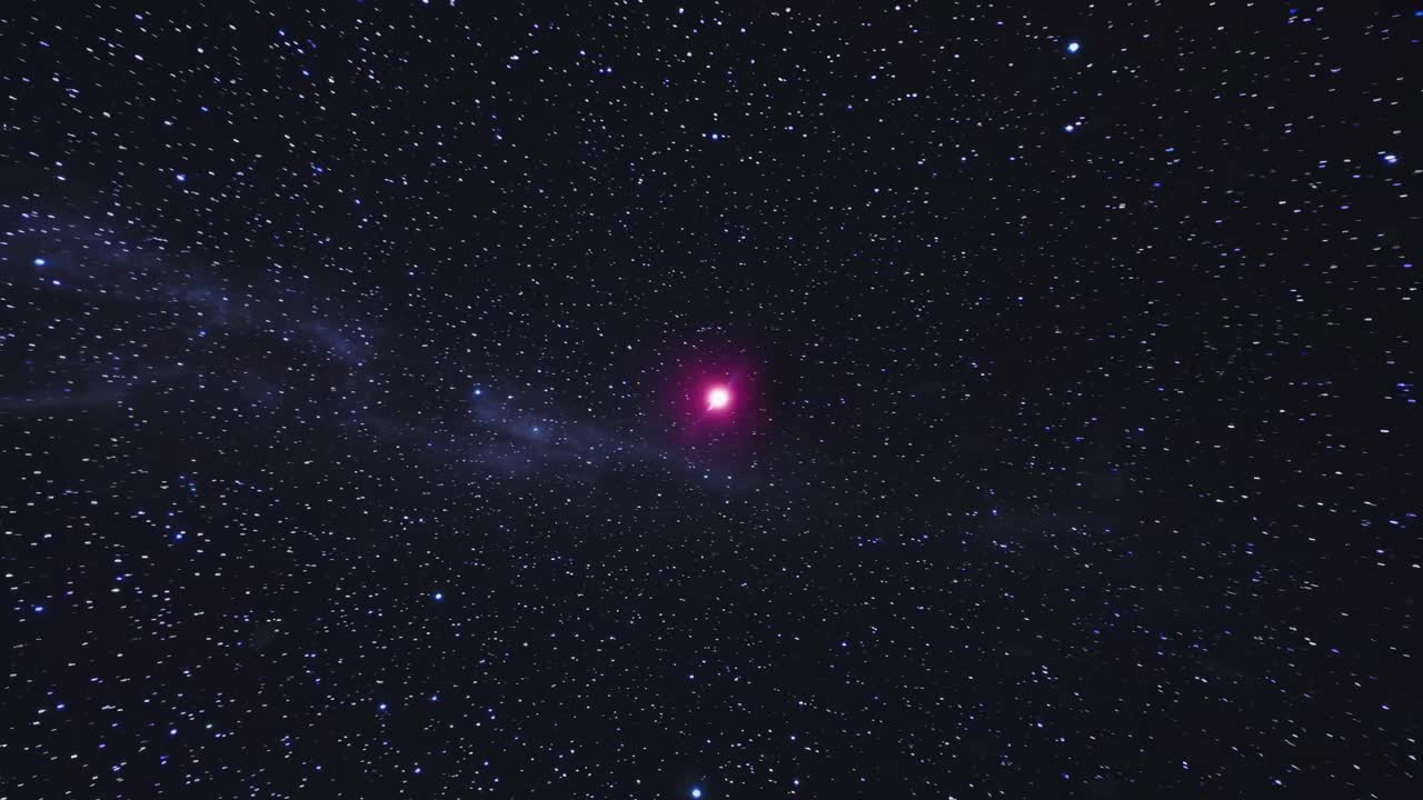 A mesmerizing video of a starry night sky with a red star at the center. The camera angle is a wide