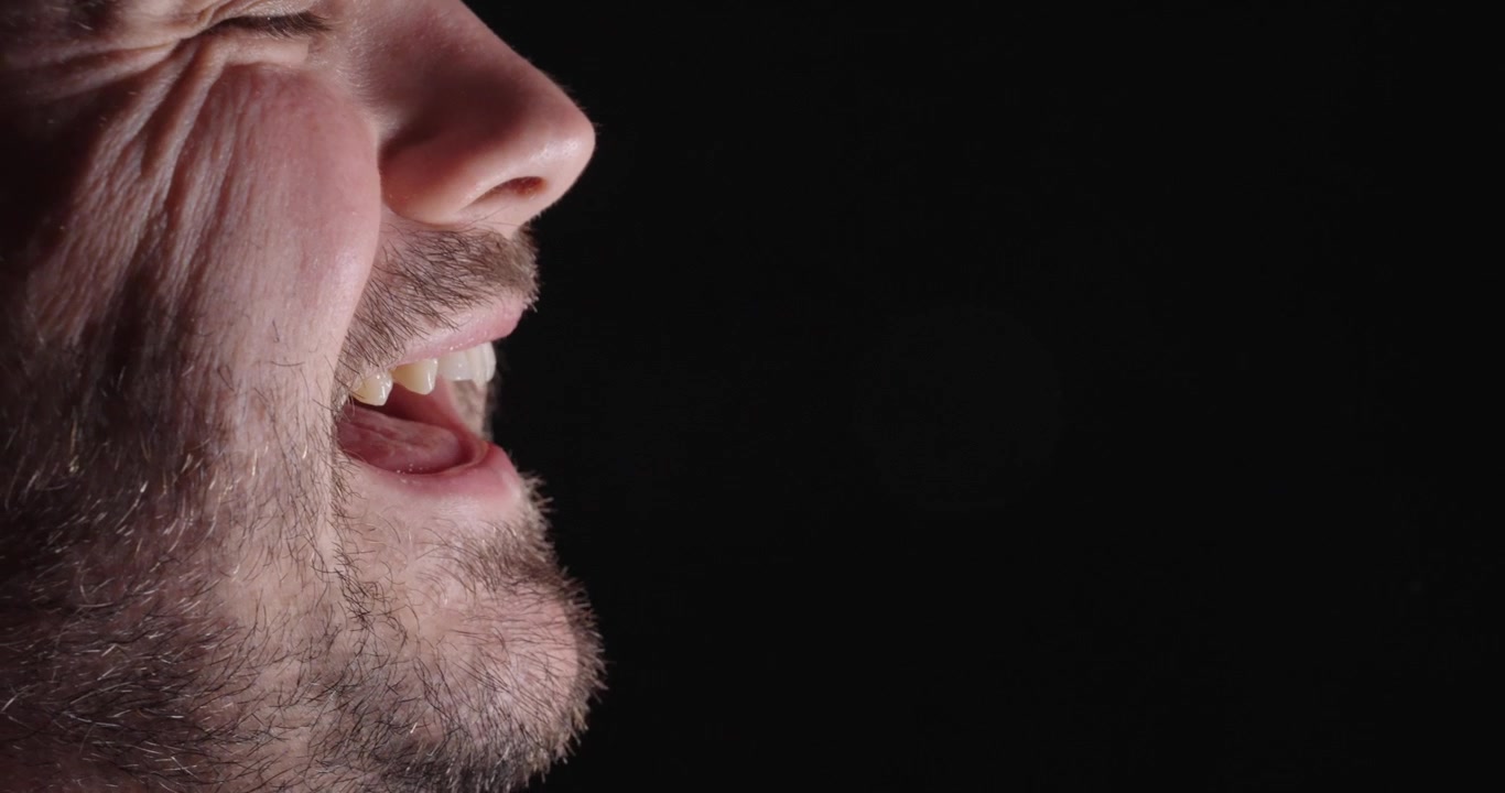 Primo piano di un uomo che parla con goccioline di saliva visibili, che illustra il parlato, la trasmissione di goccioline e la comunicazione