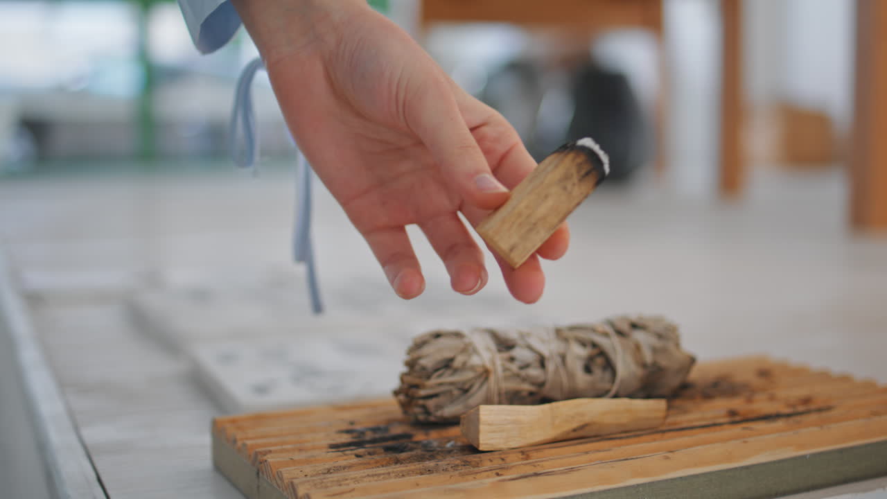 손으로 향기 막대기를 들고 실내에서 클로즈업. 팔로 산토 나무 향을 사용하는 여성