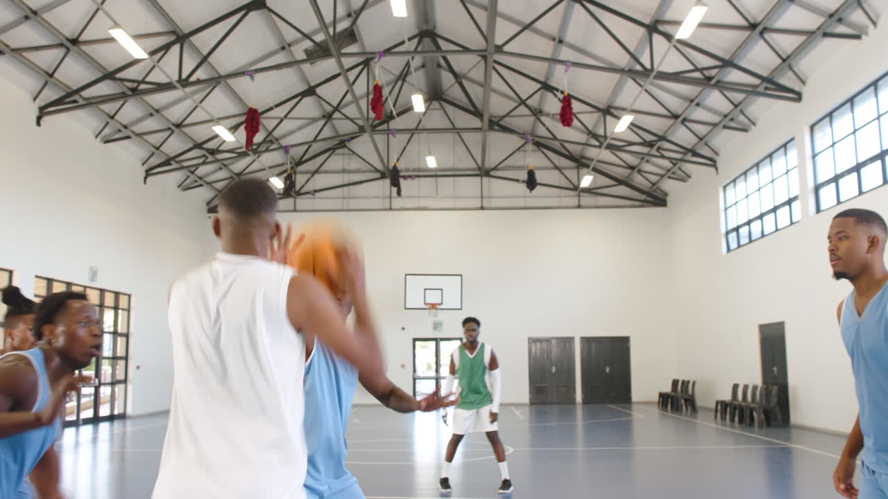 Multiracial male basketball players playing basketball, passing and throwing in gym