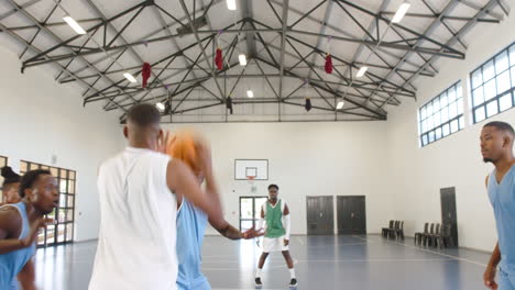 multiracial male basketball players playing basketball, passing and throwing in gym