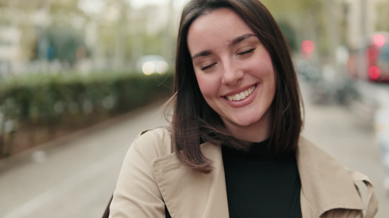 Mujer joven sonriendo felizmente a la cámara en una calle de la ciudad