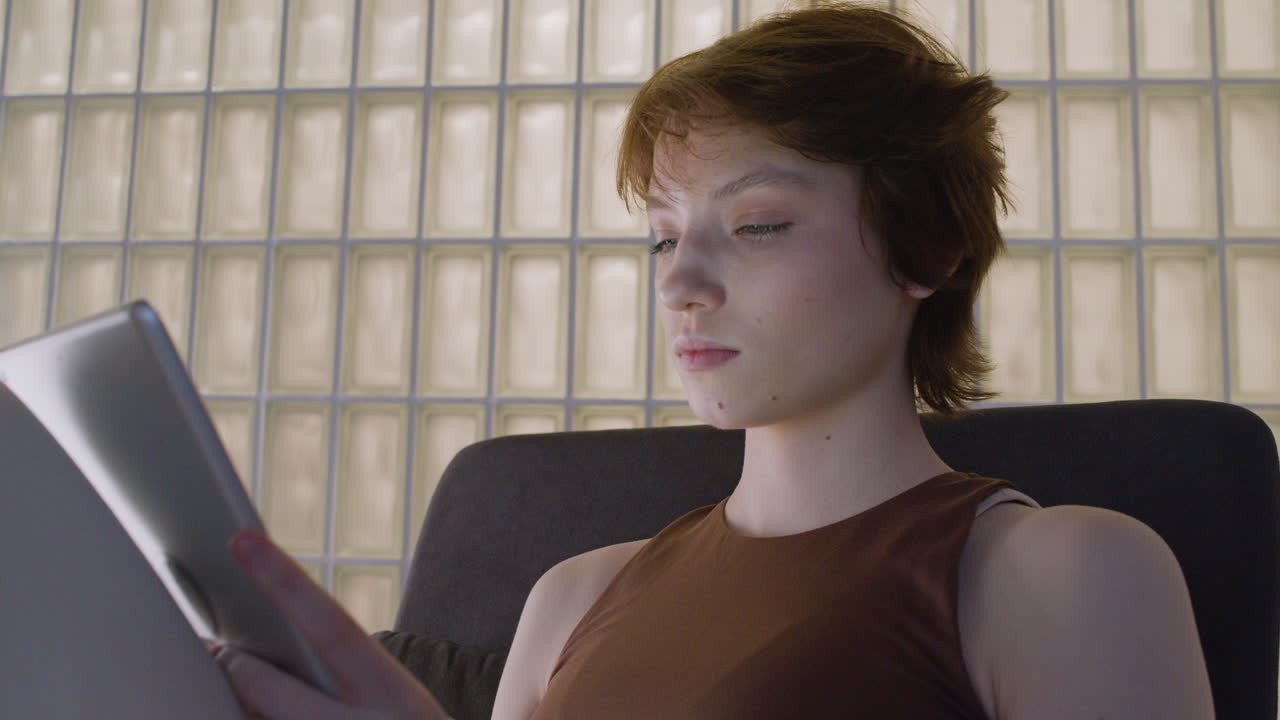 태블릿을 사용하여 의자에 앉아 있는 피곤한 소녀의 밑면