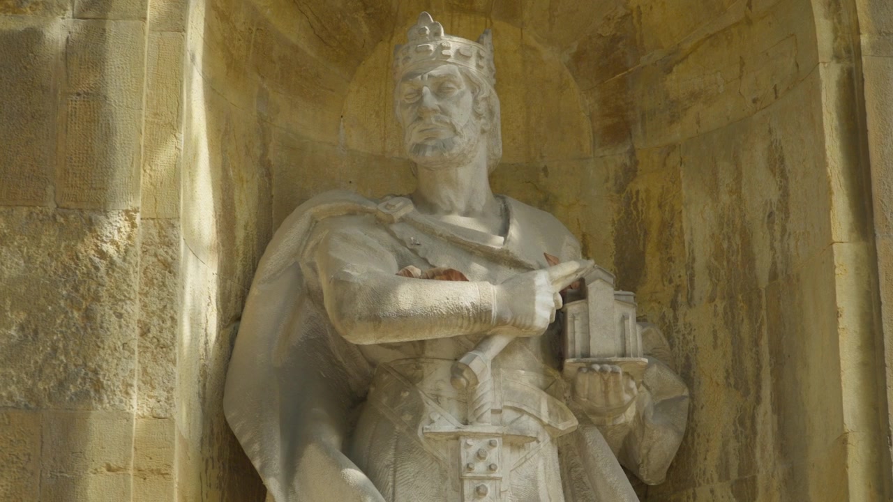 Inquadratura media frontale di una statua di re incoronato scolpita in una nicchia di pietra