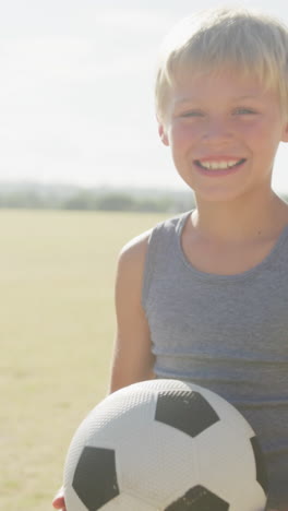 video of happy caucasian boy holding ball on sports field