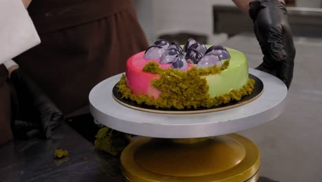 mousse cake with green and pink mirror icing on the turntable in the kitchen.