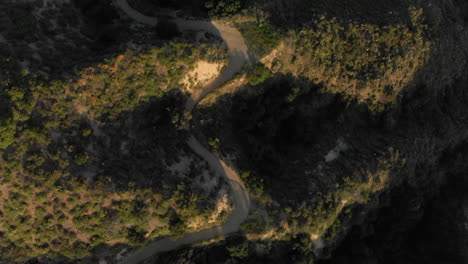 Panorámica-Aérea-E-Inclinación-Hacia-Abajo-Desde-Un-Camino-Sinuoso-Hasta-Una-Montaña-Verde