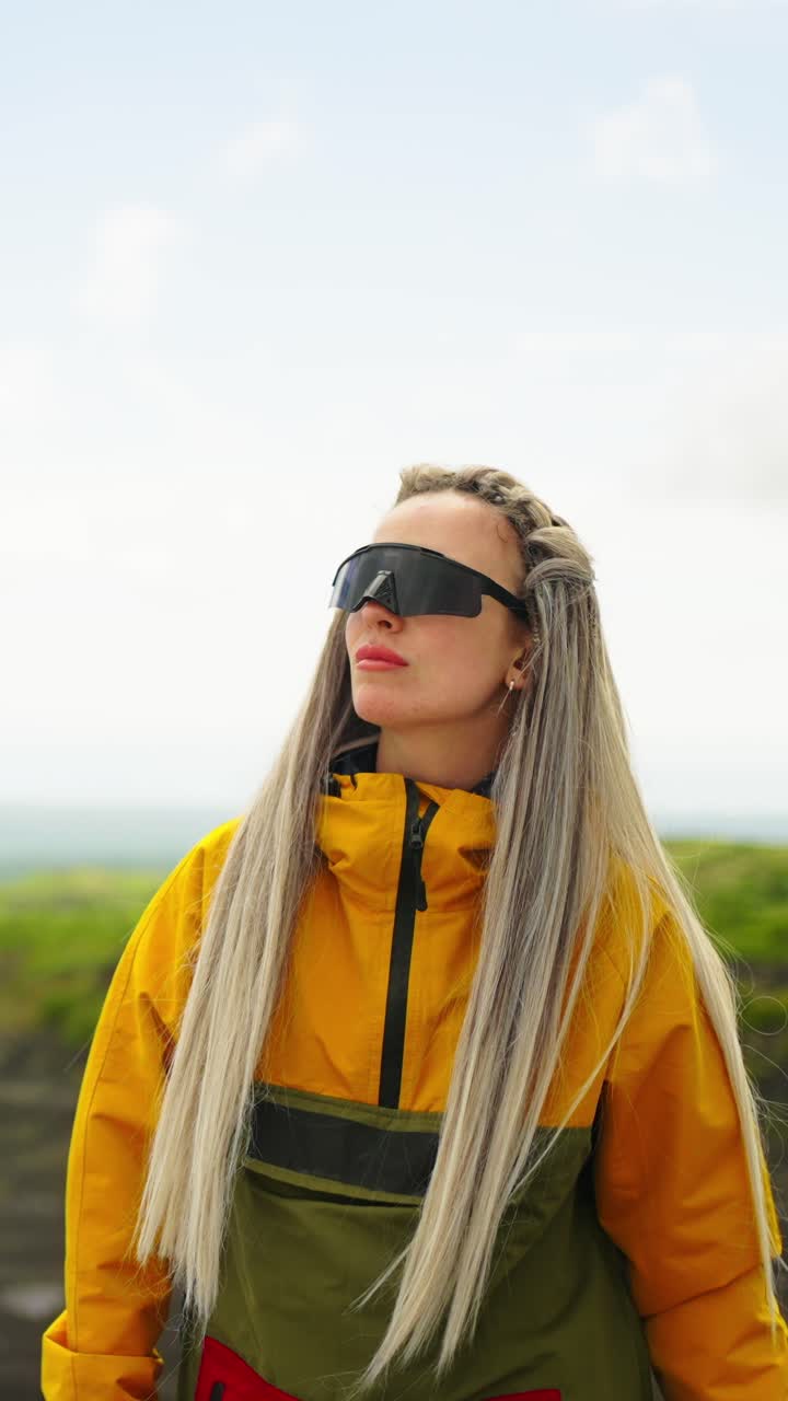 Young Woman in Colorful Outdoor Jacket and Sunglasses Looking Around