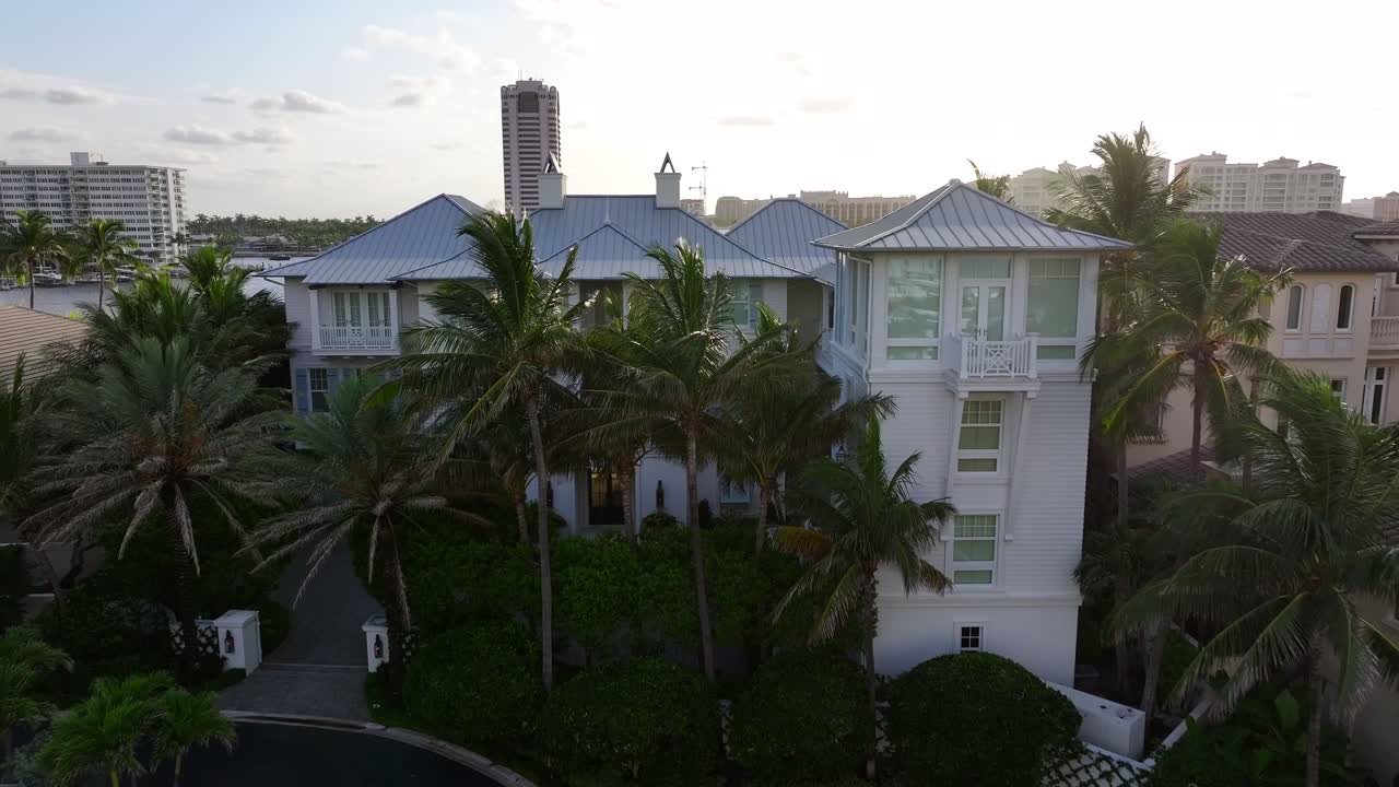 Aerial establishing shot of Boca Raton Town with luxury mansion and villas at sunset. Private waterway entry. Boat parking on river at golden hour. Florida, United States America.Drone forward flight.