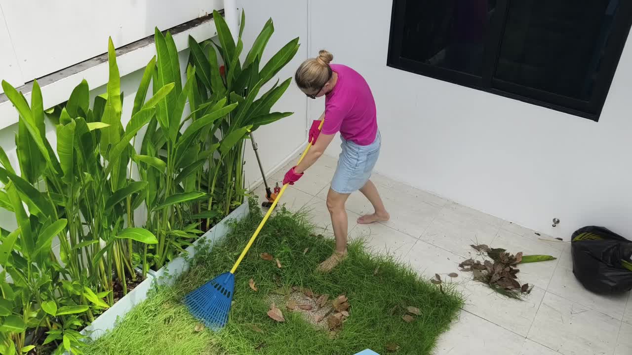 mujer barriendo hojas en el patio trasero