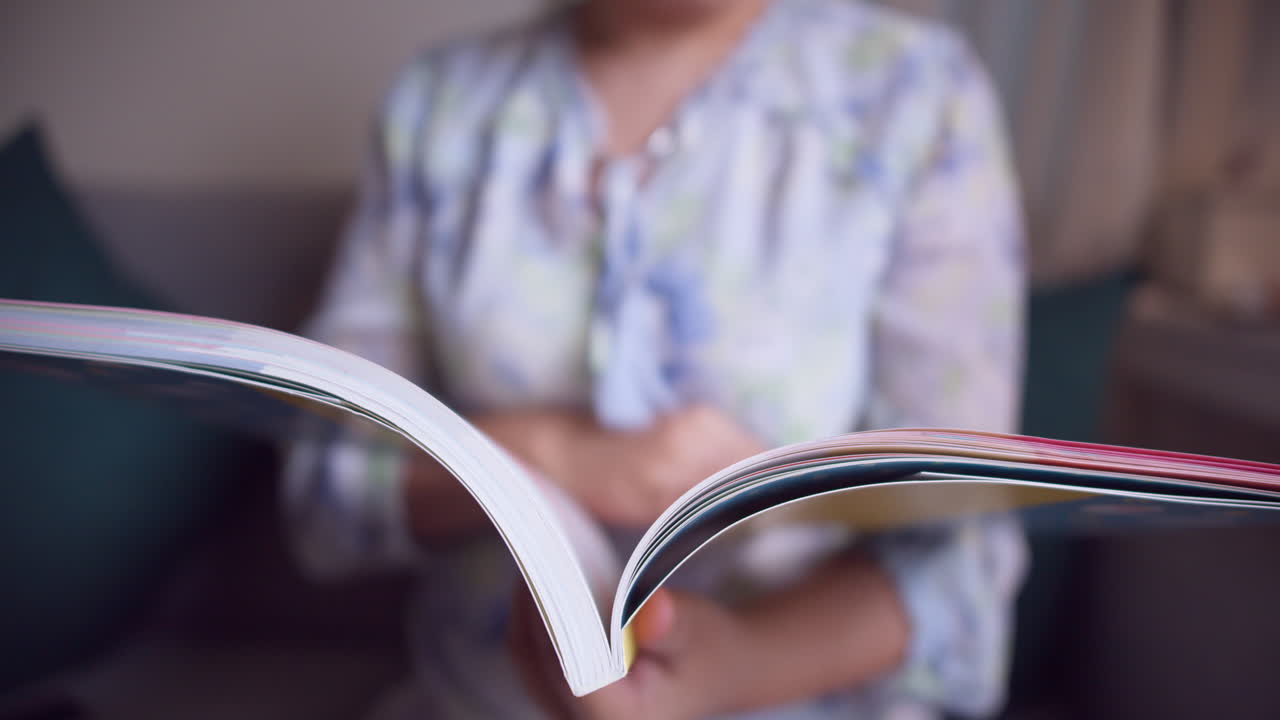 un primer plano de una mano con una revista, absorta en la lectura