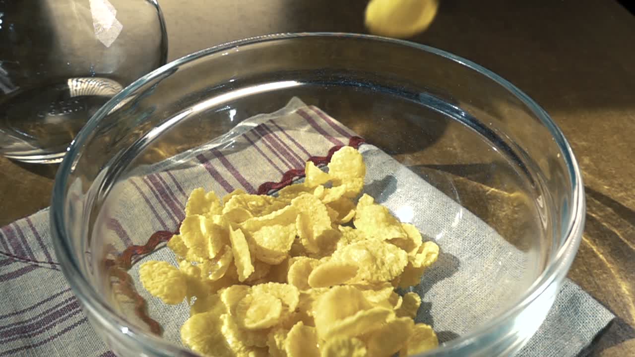 Fiocchi di mais gialli croccanti nella ciotola per una deliziosa colazione mattutina con latte. Slow motion con ripresa rotatoria.