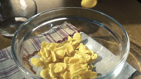 crispy yellow corn flakes into the bowl for the morning a delicious breakfast with milk. slow motion with rotation tracking shot.