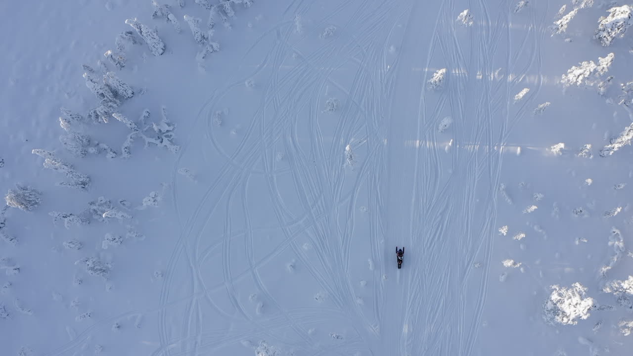 vista superior de la toma de drones de paseos en moto de nieve en un campo de nieve abierto en branäs, suecia