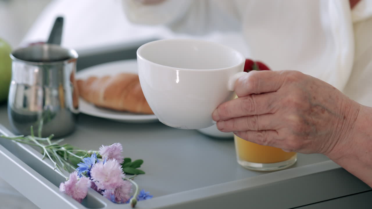 Signora anziana che versa e gusta il caffè mattutino a letto