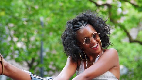 trendy young black woman wearing round sunglasses and camisole having fun and laughing outdoors, close up