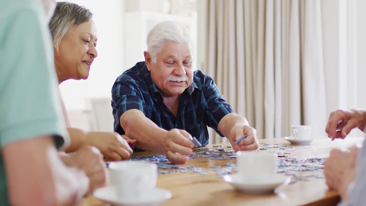 hombre caucásico mayor feliz haciendo rompecabezas en casa con diversos amigos mayores, cámara lenta