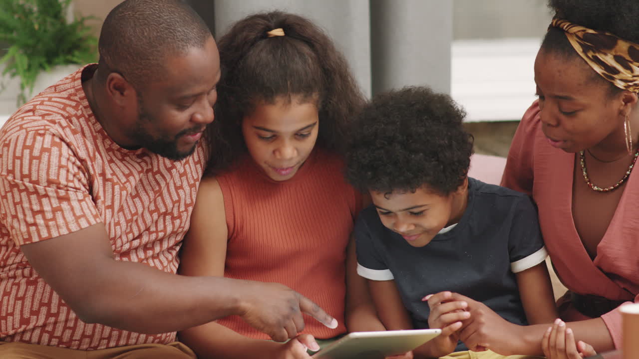 Famiglia afroamericana di quattro persone che gioca con un tablet