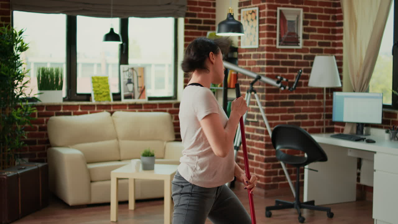 Silly woman mopping floors with washing solution and dancing in living room